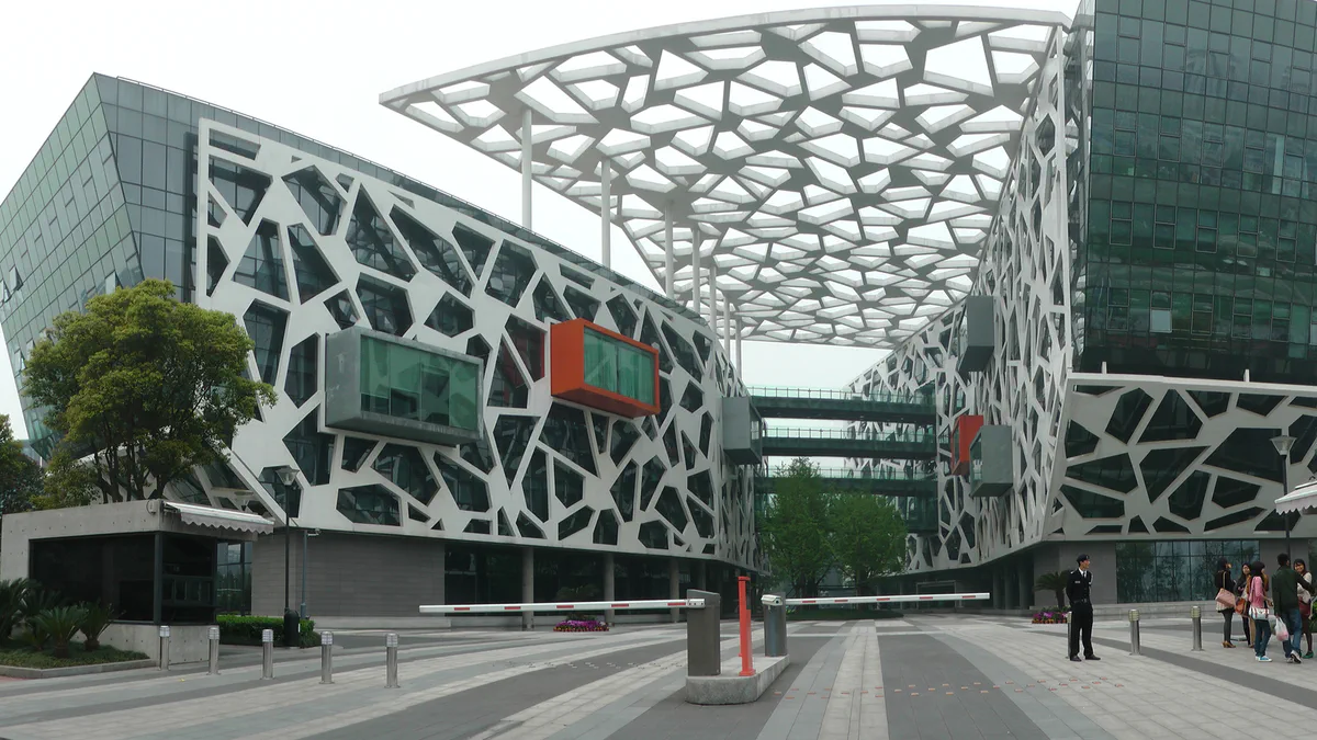 A wide view of the Alibaba Group headquarters campus in Hangzhou under a bright sky, with several office towers and low buildings.