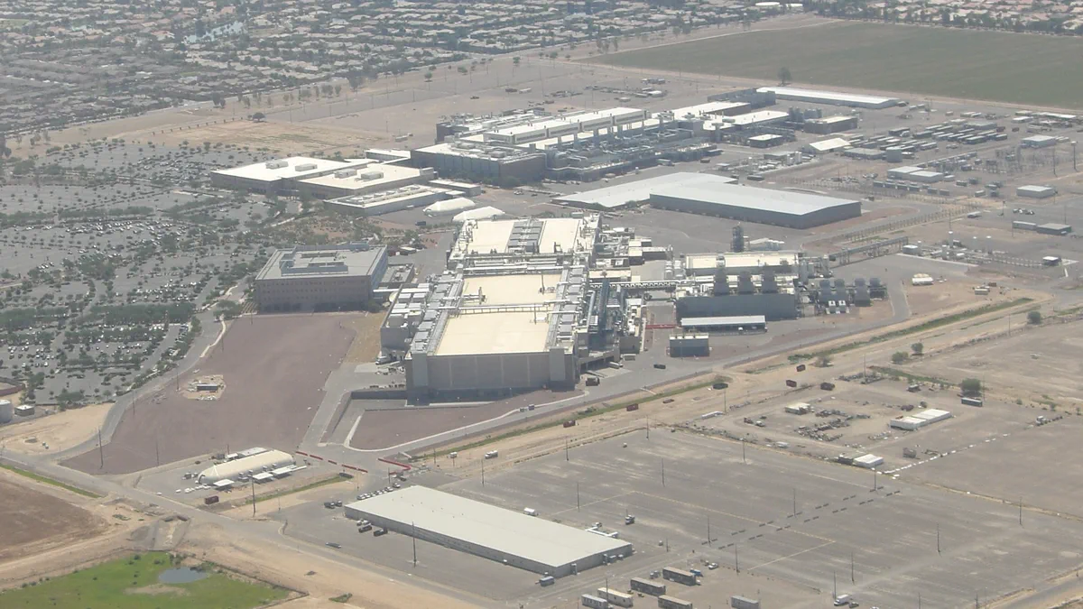 Aerial view of Intel's fabrication complex in Chandler, Arizona, showing long white-roofed factory buildings, parking areas and desert around the site.